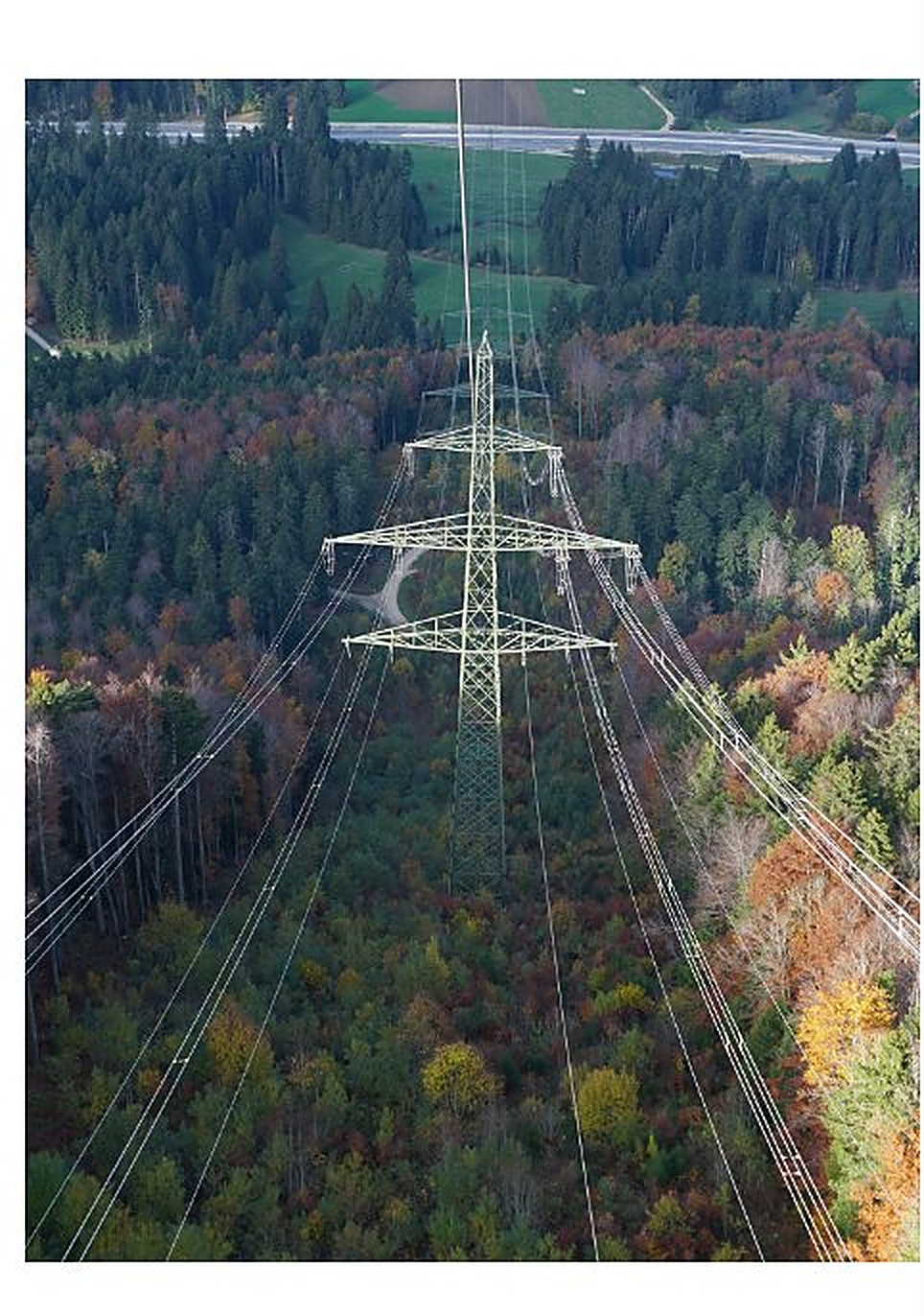 High-voltage transmission tower across forested landscape