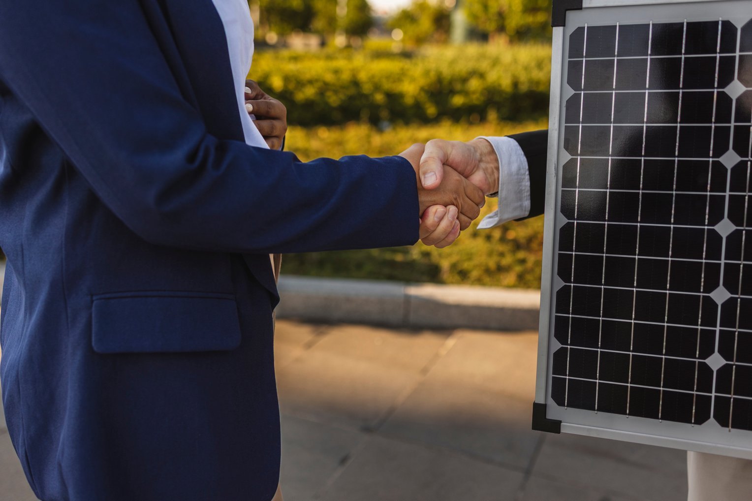 Business handshake beside a solar panel
